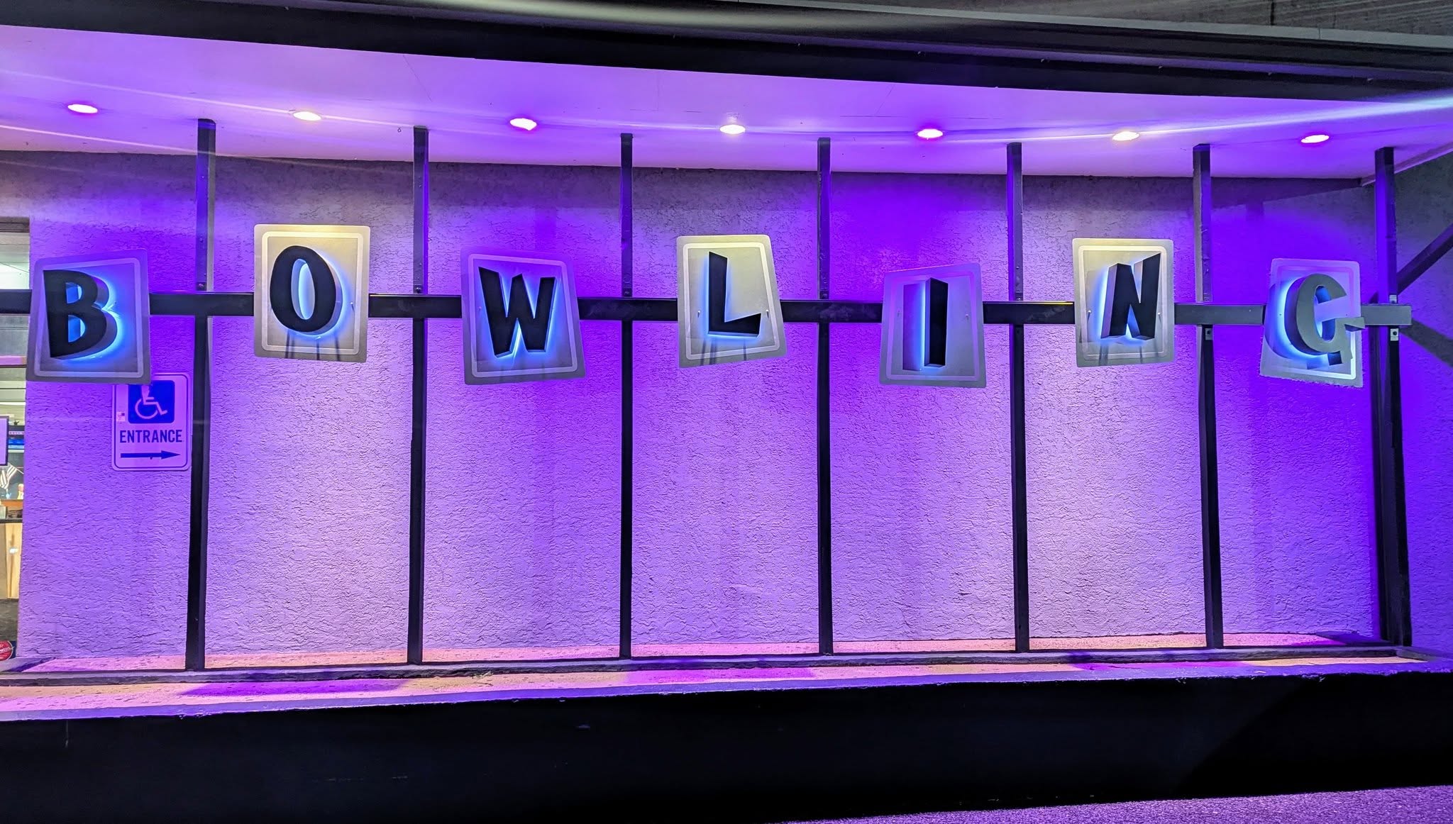The blacklit purple BOWLING sign glowing at Westbrook Lanes during a cosmic night